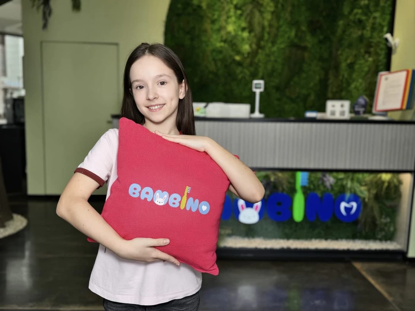 Девочка с фирменной подушкой BAMBINO у стойки ресепшн